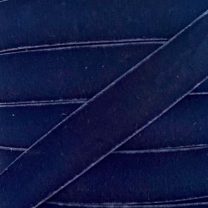 May include: A close-up of a roll of dark blue velvet ribbon. The ribbon is soft and has a subtle sheen.