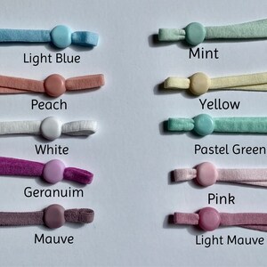 May include: Assortment of 10 colors of elastic cord with plastic stoppers. Colors include light blue, peach, white, geranium, mauve, mint, yellow, pastel green, pink, and light mauve.