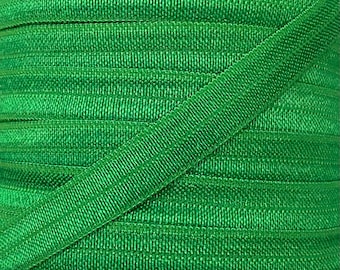 May include: A spool of green grosgrain ribbon. The ribbon is folded and stacked on itself, creating a diagonal pattern.