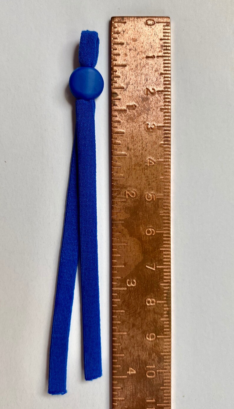 May include: A pair of blue elastic mask extenders with a blue plastic adjuster. The extenders are about 8 inches long and are measured against a ruler.