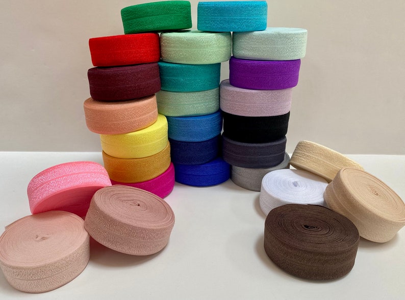 Puede incluir: Una colecci&oacute;n de bandas el&aacute;sticas coloridas en varios tonos, incluyendo rosa, rojo, verde, azul y morado. Algunas est&aacute;n apiladas, otras enrolladas. Las bandas son de tela texturizada.