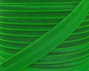 May include: Green elastic ribbon with a ribbed texture. The ribbon is folded in half and the ribbed texture is visible on both sides.
