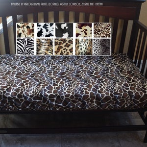 May include: A brown and white fitted crib sheet with a giraffe print. The sheet is available in various animal prints, including leopard, western cowboy, zebra, and cheetah.