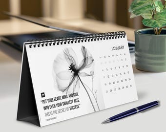 May include: A white desk calendar with a black wire spiral binding, featuring a black and white x-ray style flower illustration, the month of January, and the quote: "Put your heart, mind, and soul into even your smallest acts. This is the secret of success."