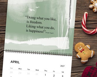 Pode incluir: Um calendário de parede para abril de 2027 com fundo verde sálvia, pinceladas brancas abstratas, dois pássaros e a citação: "Doing what you like, is freedom. Liking what you do, is happiness!" (Frank Tyger). O calendário tem uma espiral preta.