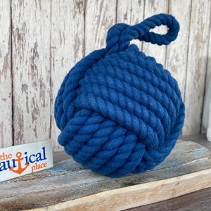 May include: A large, blue, cotton rope doorstop in the shape of a knot. The rope has a loop at the top for easy carrying.