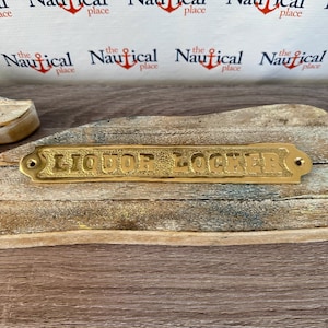 May include: A brass plaque with the words "Liquor Locker" engraved on it. The plaque is mounted on a wooden surface.