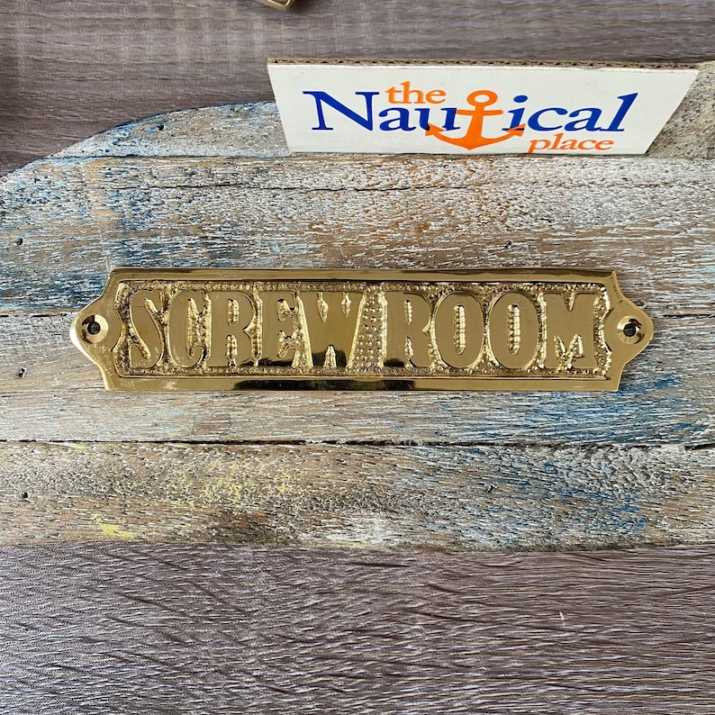 May include: A gold-coloured metal sign with the words "Screw Room" embossed on it. The sign has two small holes on either side for hanging.