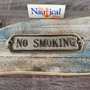 May include: A rustic wooden sign with a silver metal plaque that reads "NO SMOKING". The sign is weathered and has a distressed look.