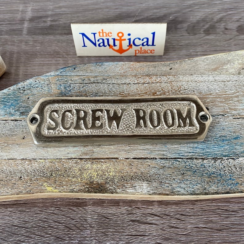 May include: A silver metal sign with the words "Screw Room" embossed on it. The sign is mounted on a weathered wooden surface.