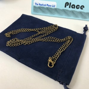 Pu&ograve; includere: Una collana a catena dorata con chiusura, presentata in una pochette di velluto blu scuro. La pochette ha una chiusura con coulisse.