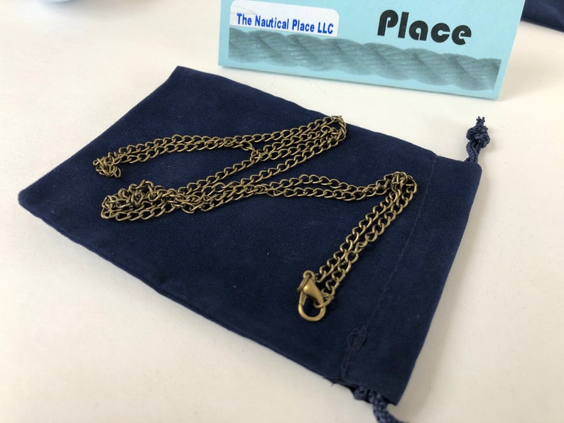 Pu&ograve; includere: Una collana a catena dorata con chiusura, presentata in una pochette di velluto blu scuro. La pochette ha una chiusura con coulisse.