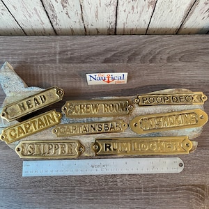 May include: A set of ten brass nautical door signs with various room names, including "Head", "Captain", "Screw Room", "Captain's Bar", "Poop Deck", "No Smoking", "Skipper", and "Rum Locker".