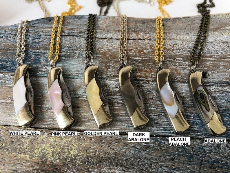 Pu&ograve; includere: Sei collane diverse con un coltellino tascabile e diverse intarsi di conchiglia. Le collane sono in ottone e hanno una catena dorata. Gli intarsi di conchiglia sono in madreperla bianca, madreperla rosa, madreperla dorata, abalone scuro, abalone pesca e abalone.