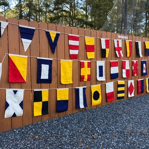 Our set of handmade nautical signal flags displayed on our fence at home. This is the highest quality set of nautical flags that you will find on etsy.