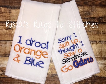 May include: Two white burp cloths with embroidered text. The first cloth says "I drool Orange & Blue". The second cloth says "Sorry I spit up, thought I saw a Seminole Go Gators".