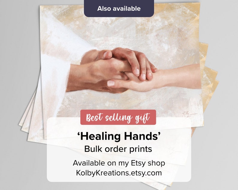 Op de afbeelding: Een schilderij van twee handen die in elkaar grijpen, de ene hand is licht van kleur en de andere donker. Het schilderij heeft de titel 'Healing Hands' en is verkrijgbaar als print. De tekst 'Best selling gift' is ook in de afbeelding opgenomen.