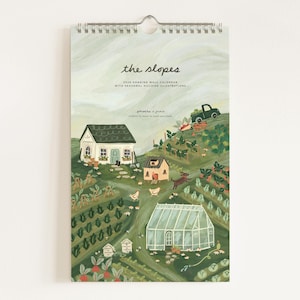 May include: A hanging wall calendar titled "the slopes" with a spiral binding and metal hook. The calendar features a colorful illustration of a hillside with houses, a greenhouse, and a truck. The text "2023 Hanging Wall Calendar with Seasonal Hillside Illustrations" is also visible.