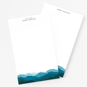 May include: A note pad with a mountain range design in shades of blue. The text "A note from Henry Kessler" is printed at the top of the pad.
