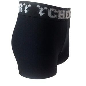 May include: Black athletic shorts with a white waistband. The waistband features the text "VERY CHEER" in white block letters with a cheerleader graphic. The shorts are made of a stretchy material.