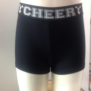 May include: Black athletic shorts with a white waistband featuring the word "CHEER" in a block letter design. The shorts are displayed on a mannequin.