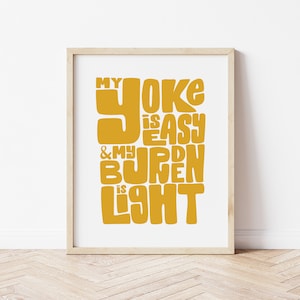 May include: A framed print with a yellow text design that reads "My yoke is easy & my burden is light".