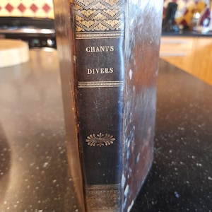 May include: A vintage, leather-bound book with gold lettering on the spine. The title is "CHANTS DIVERS".
