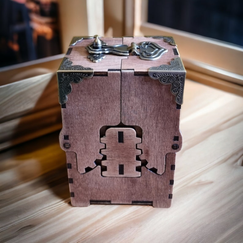 May include: A wooden box with a hinged lid and intricate metal hardware. The box is a warm brown color, with decorative corner accents and a clasp. The design features a unique interlocking mechanism on the front.