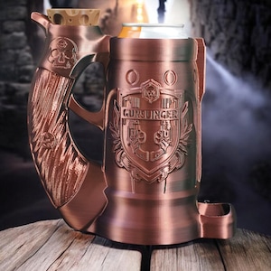 May include: A copper-colored metal mug with a skull design on the handle and the word "GUNSLINGER" embossed on the front. The mug is designed to hold a can of beverage.