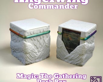 May include: White deck box with an angel wing design, featuring the text "Angelwing Commander" and "Magic: The Gathering Deck Box." The box has a rainbow-colored accent and holds a card. The box is designed to store trading cards.