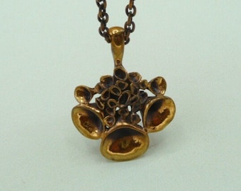Peut inclure: Un collier avec un pendentif en forme de fleur en or. Le pendentif est composé d'un groupe de petites formes rondes qui ressemblent à des fleurs. Le collier est fait d'une chaîne au design simple.