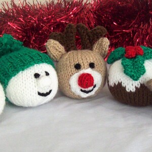 Puede incluir: Cinco adornos navide&ntilde;os de punto: Pap&aacute; Noel, mu&ntilde;eco de nieve, reno, pud&iacute;n navide&ntilde;o y un petirrojo. Los adornos son todos blancos, rojos, verdes y marrones.