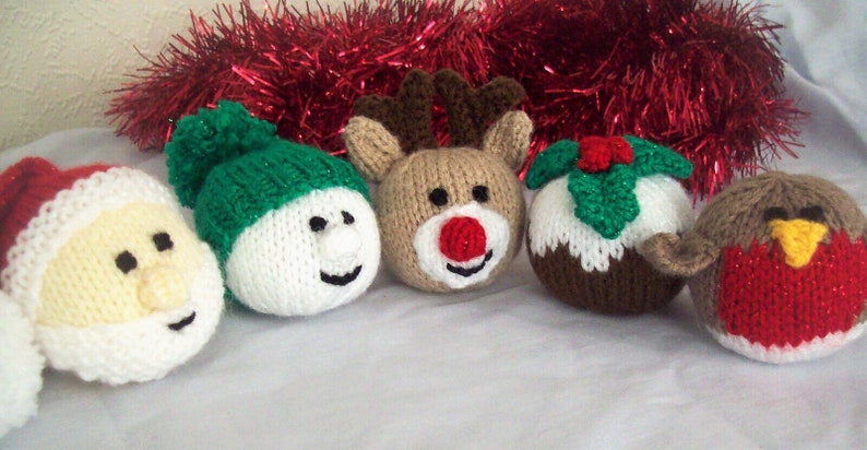 Puede incluir: Cinco adornos navide&ntilde;os de punto: Pap&aacute; Noel, mu&ntilde;eco de nieve, reno, pud&iacute;n navide&ntilde;o y un petirrojo. Los adornos son todos blancos, rojos, verdes y marrones.