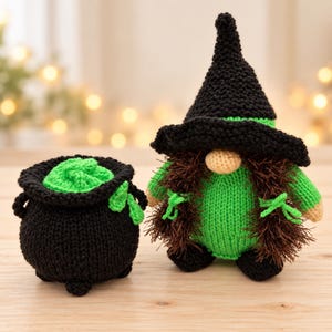 May include: A knitted figurine wearing a black pointed hat and green shirt with brown yarn hair, positioned next to a black knitted cauldron filled with green yarn. The figurine has a beige nose and small black feet, while the cauldron has three feet.