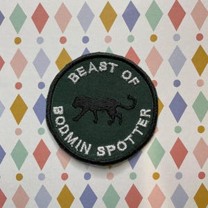 May include: A green circular patch with white embroidered text that reads "Beast of Bodmin Spotter" and a black panther silhouette in the centre.