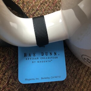 Puede incluir: Una etiqueta azul y blanca con el texto "RAE DUNN. ARTISAN COLLECTION BY MAGENTA&trade;" y "Magenta, Inc. Berkeley, CA 94710".