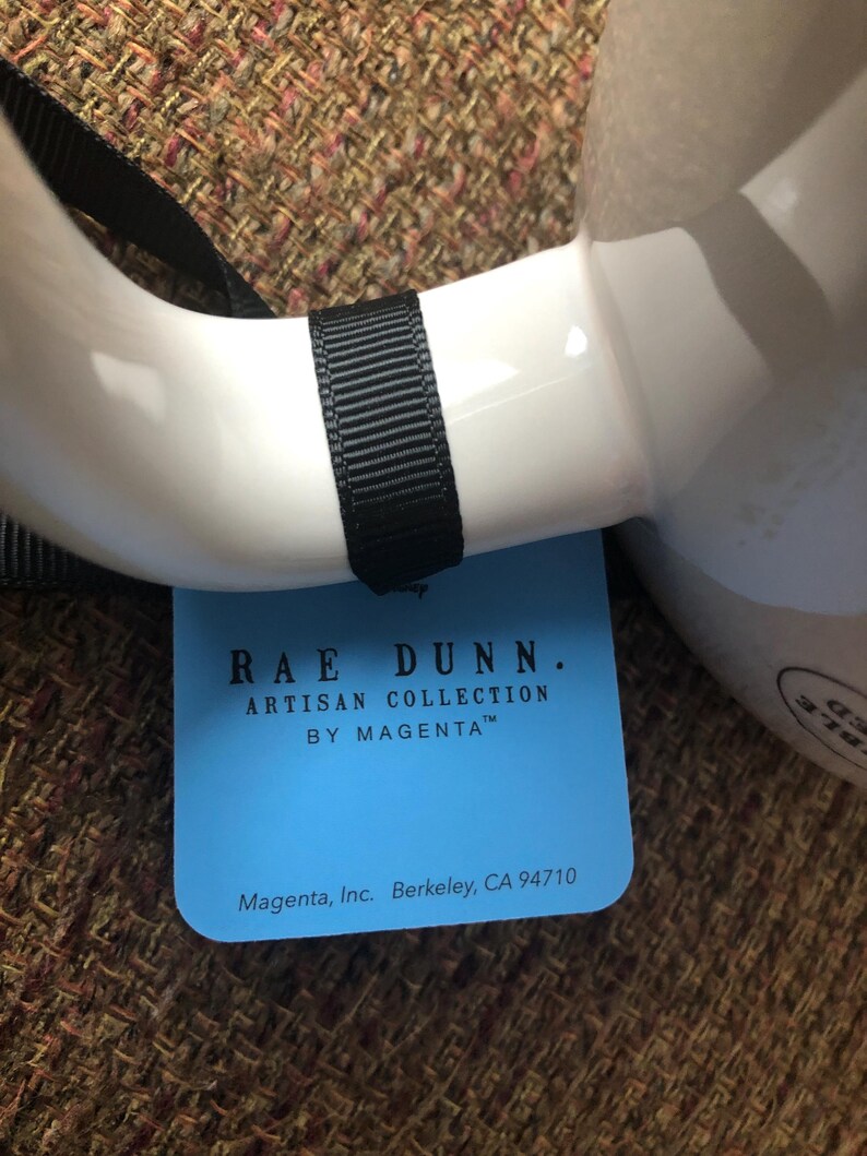 Puede incluir: Una etiqueta azul y blanca con el texto "RAE DUNN. ARTISAN COLLECTION BY MAGENTA&trade;" y "Magenta, Inc. Berkeley, CA 94710".