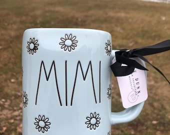 Taza nueva azul "Mimi" de Rae Dunn con margaritas negras.