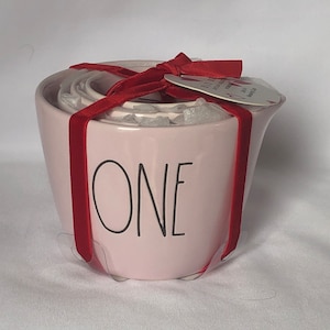 Può includere: Set di tazze da misura in ceramica rosa con un nastro rosso e un'etichetta che dice "One".
