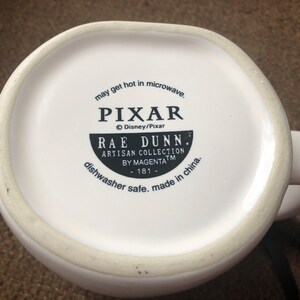 Puede incluir: Taza de cer&aacute;mica blanca con un dise&ntilde;o en blanco y negro que dice "may get hot in microwave. PIXAR &copy; Disney/Pixar RAE DUNN. ARTISAN COLLECTION BY MAGENTATM -181- dishwasher safe. made in china."