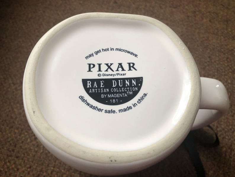 Puede incluir: Taza de cer&aacute;mica blanca con un dise&ntilde;o en blanco y negro que dice "may get hot in microwave. PIXAR &copy; Disney/Pixar RAE DUNN. ARTISAN COLLECTION BY MAGENTATM -181- dishwasher safe. made in china."