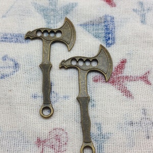 以下が含まれることがあります： 装飾的なハンドルが付いた斧の形をしたアンティークゴールド調の金属製のボトルオープナーが2つ。