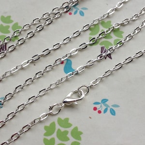 May include: A silver chain necklace with a lobster clasp closure. The chain is made of small, oval-shaped links.