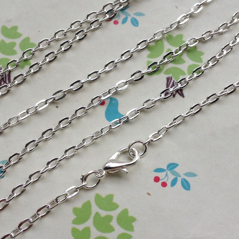 May include: A silver chain necklace with a lobster clasp closure. The chain is made of small, oval-shaped links.
