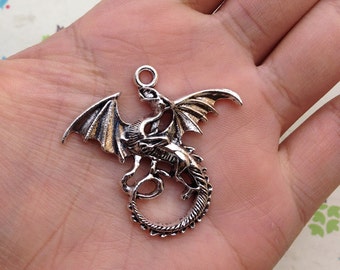 May include: Silver-toned dragon charm pendant with intricate details. The dragon is curled up with its wings spread out.