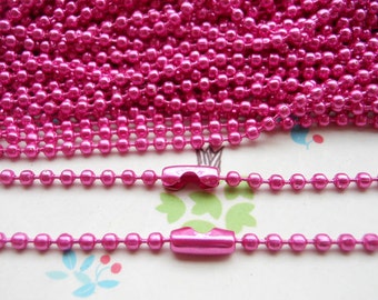 May include: A close-up of a pink metal chain with a shiny finish. The chain is made of small, round links and is perfect for crafting jewelry or other projects.