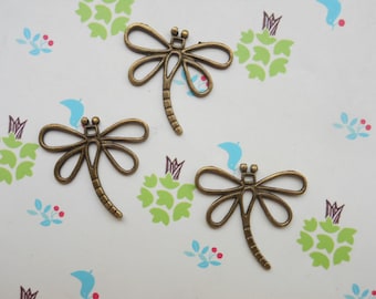 May include: Three antique gold-toned dragonfly charms. The charms are made of metal and have a detailed design.