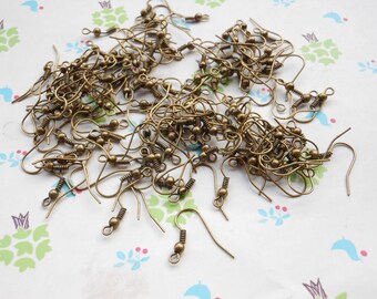 May include: A pile of bronze-colored earring hooks with a small ball at the end of each hook.