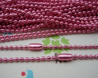 May include: A close-up of a pink metal chain with a shiny finish. The chain is made of small, round links and is perfect for crafting jewelry or other projects.