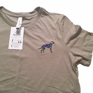 Peut inclure: Un t-shirt gris avec un motif de chien géométrique brodé sur la poitrine gauche. L'étiquette sur le t-shirt indique "Wetherby Mercantile Co."